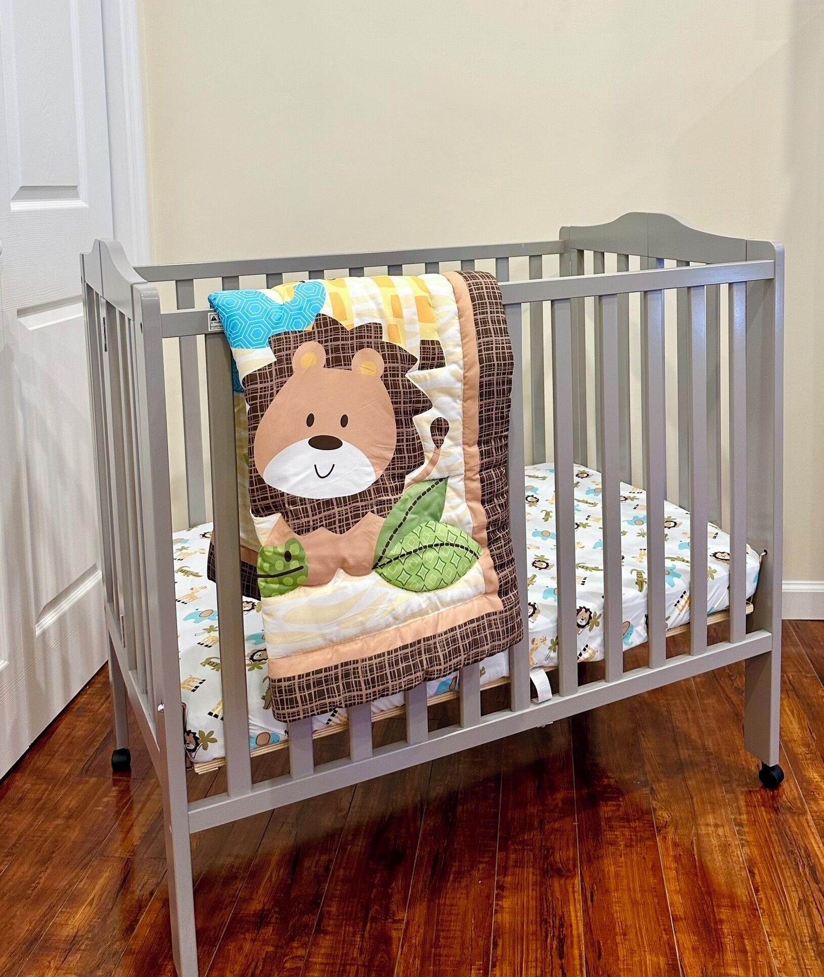 Una cuna con ropa de cama temática de leones y una almohada estampada.