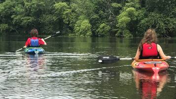 Twee kajaks op een rustig wateroppervlak met weelderige begroeiing op de achtergrond.