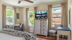 Un dormitorio con cama, escritorio, silla, televisor y armario.