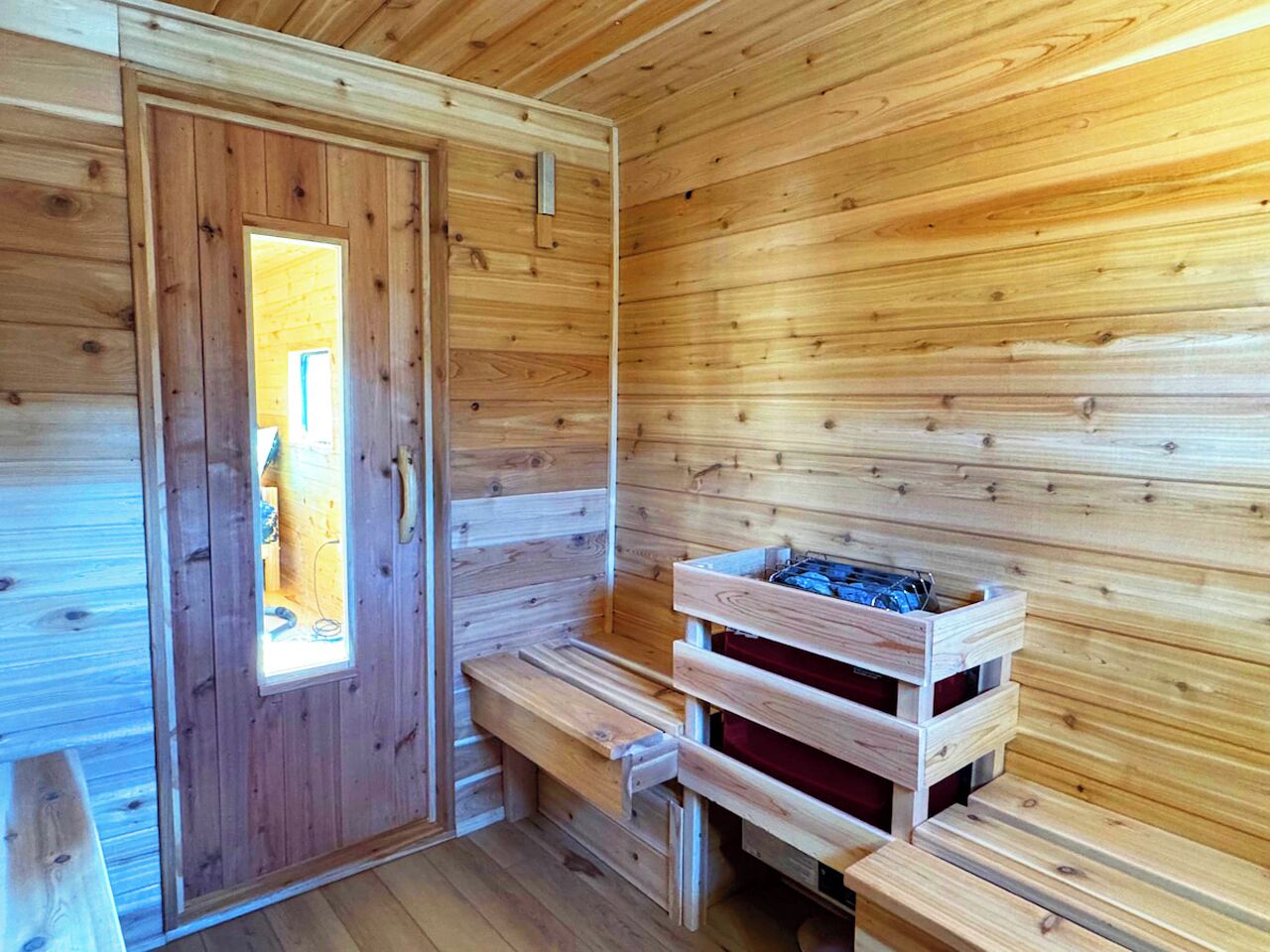 A wooden sauna room with benches and a bench with a storage compartment.