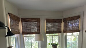 A bedroom with a large bed, a nightstand, a lamp, and a window with blinds.