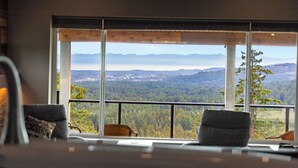 A room with a large window offering a scenic view of mountains and a forested area. - 360⁰ Views at The Feather (Victoria)