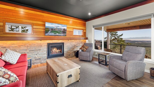 A cozy living room with a fireplace, comfortable seating, and a large window overlooking a scenic view. - 360⁰ Views at The Feather (Victoria)