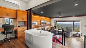 A modern room with a large bathtub, wooden cabinets, a desk, and a view of the outdoors. - 360⁰ Views at The Feather (Victoria)