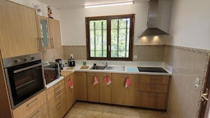 A kitchen with wooden cabinets, a double oven, a sink, and a window with a view of greenery.