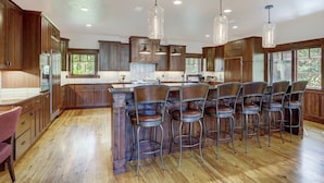 Una cocina amplia con armarios de madera, una isla central con taburetes de bar e iluminación colgante.