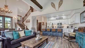 A spacious living area with a leather sofa, wooden coffee table, and a kitchen with white cabinets and a stone backsplash.