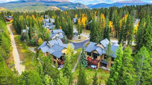 A resort with multiple buildings surrounded by dense forests and mountains in the background.