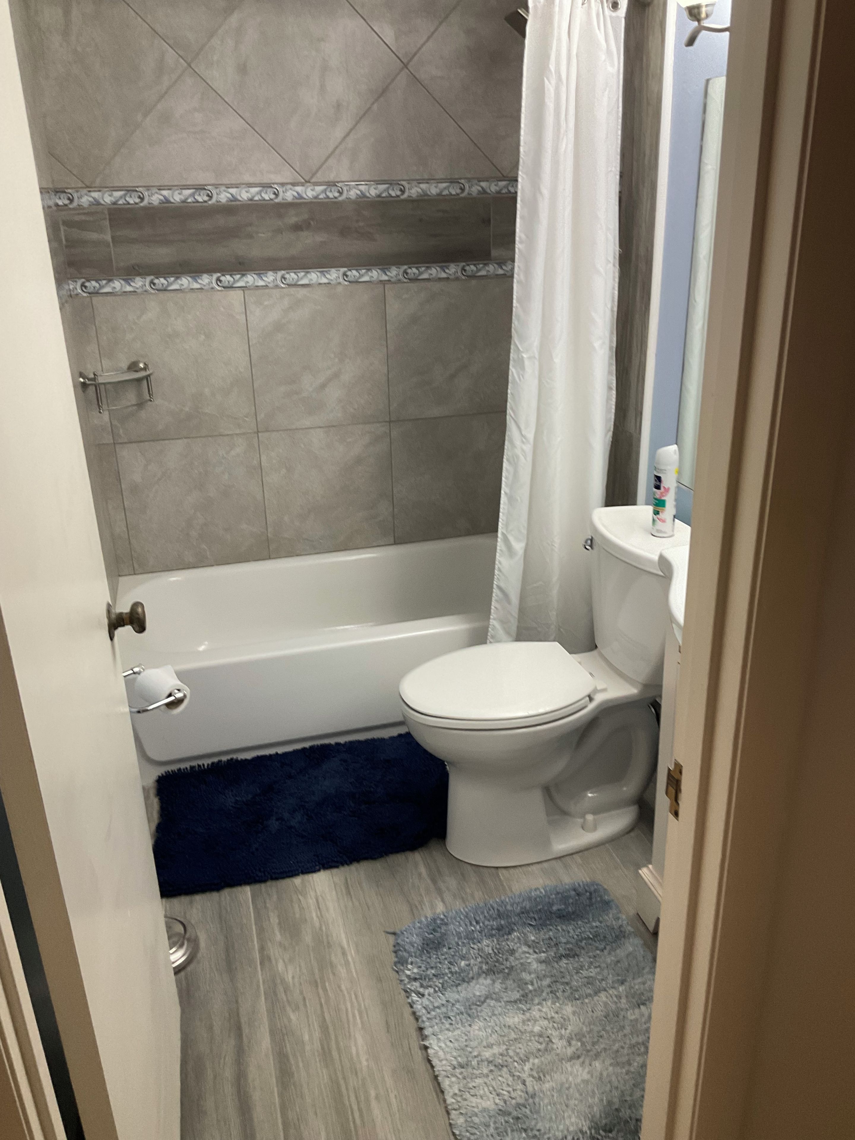 A bathroom with a bathtub, toilet, and shower curtain.