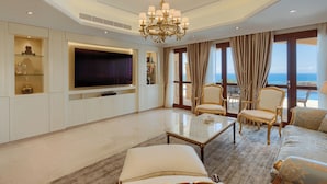 Een ruime woonkamer met een grote flatscreen-tv, comfortabele zitplaatsen en uitzicht op zee door grote ramen.