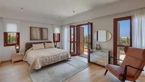 Une chambre à coucher avec un lit, une commode, une chaise et une grande fenêtre.
