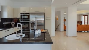 Une cuisine moderne dotée d’appareils électroménagers en acier inoxydable, d’un plan de travail noir et d’un îlot central équipé d’un évier et d’une machine à café.