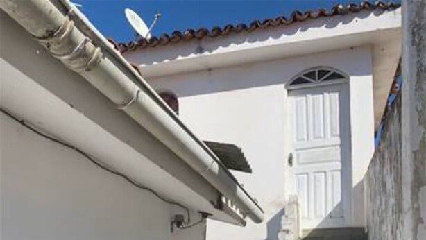 A narrow stairway leading to a white door with a window, surrounded by white walls and a tiled roof. - Studio (unfurnished) Monthly (Neópolis Natal)