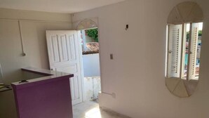A room with a purple counter, a white door, and a window with a view of the outside. - Studio (unfurnished) Monthly (Neópolis Natal)