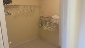 Un dressing avec espace pour suspendre les vêtements et des étagères.