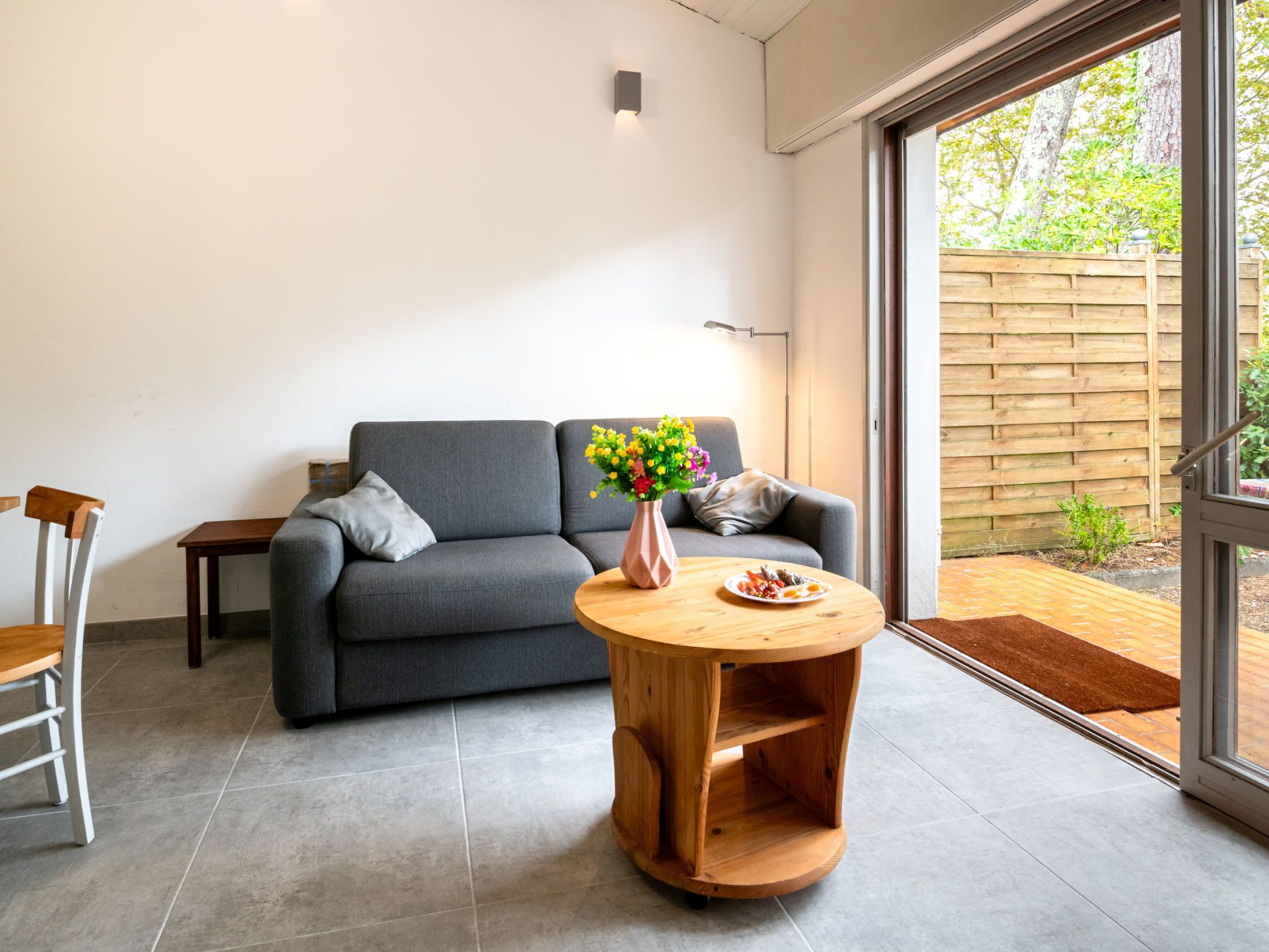 A modern living room with a grey sofa, a wooden coffee table, and a chair.