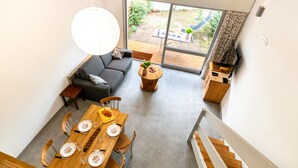 A modern interior with a dining area, sofa, and a view of the outdoors. - Hameau du courant by Interhome (Mimizan)