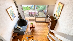 Un comedor con una mesa y sillas de madera, un sofá y vistas al jardín a través de puertas de vidrio.