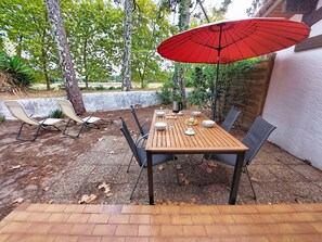 An outdoor patio with a wooden table, chairs, and a red umbrella. - Hameau du courant by Interhome (Mimizan)