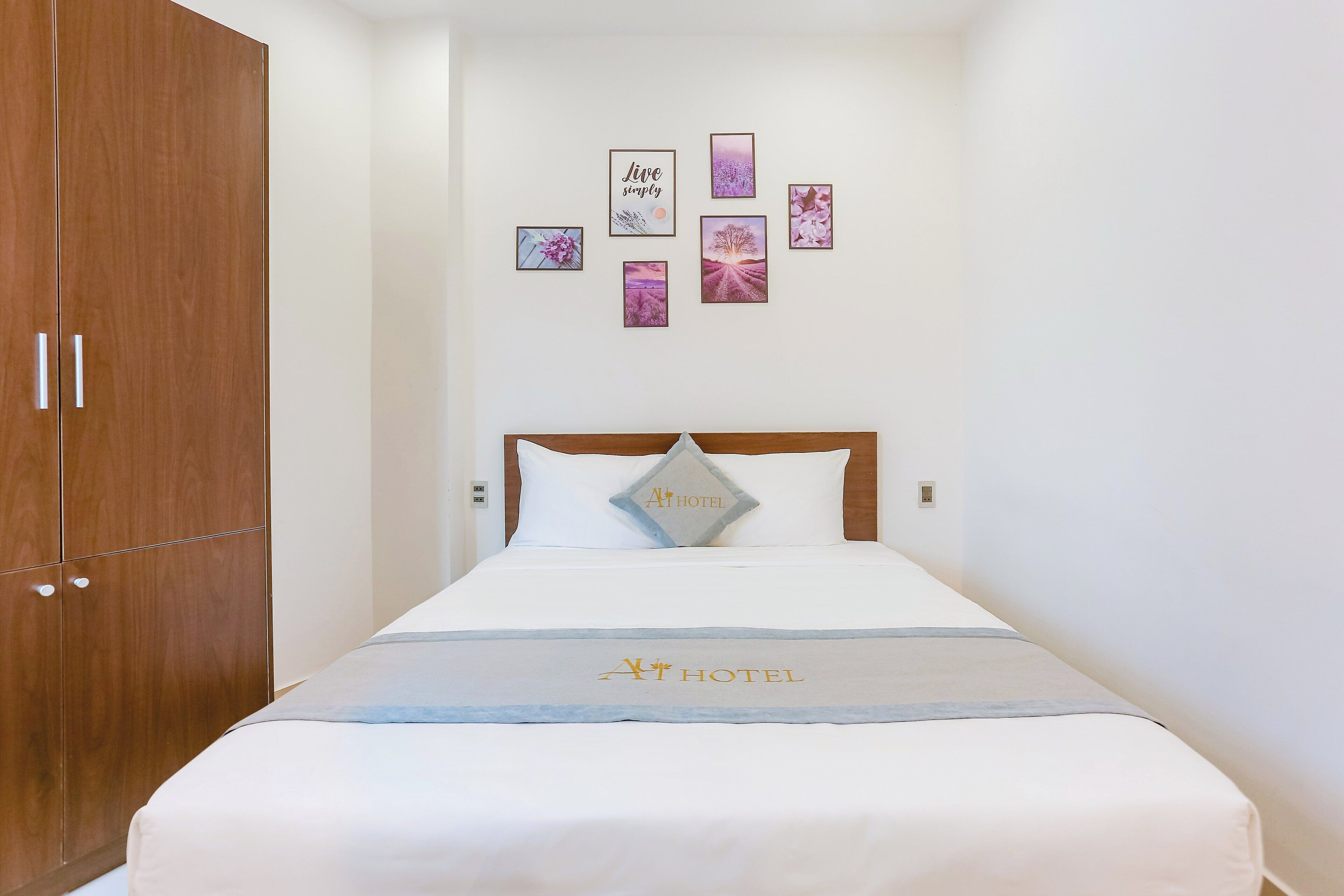 A hotel room with a bed, a wardrobe, and wall art.