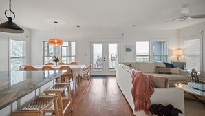 A spacious living area with a dining table, wooden chairs, a sofa, and a ceiling fan. - Waterfront Fairhope Home / Private Pier, Bayfront Views, Screened in Porch (Fairhope)