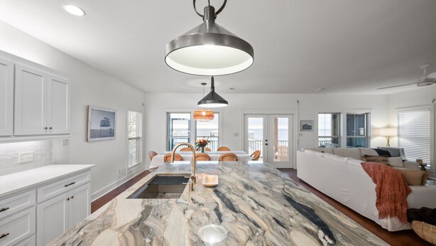 A modern kitchen with white cabinetry, a marble island, and pendant lighting. - Waterfront Fairhope Home / Private Pier, Bayfront Views, Screened in Porch (Fairhope)