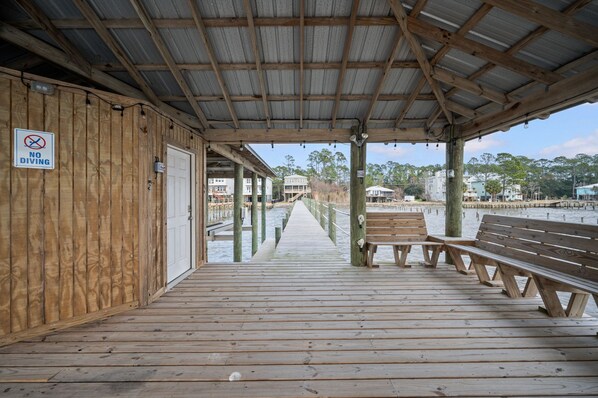 Un muelle de madera con bancos, una zona cubierta y un cartel que indica 'No Diving'.