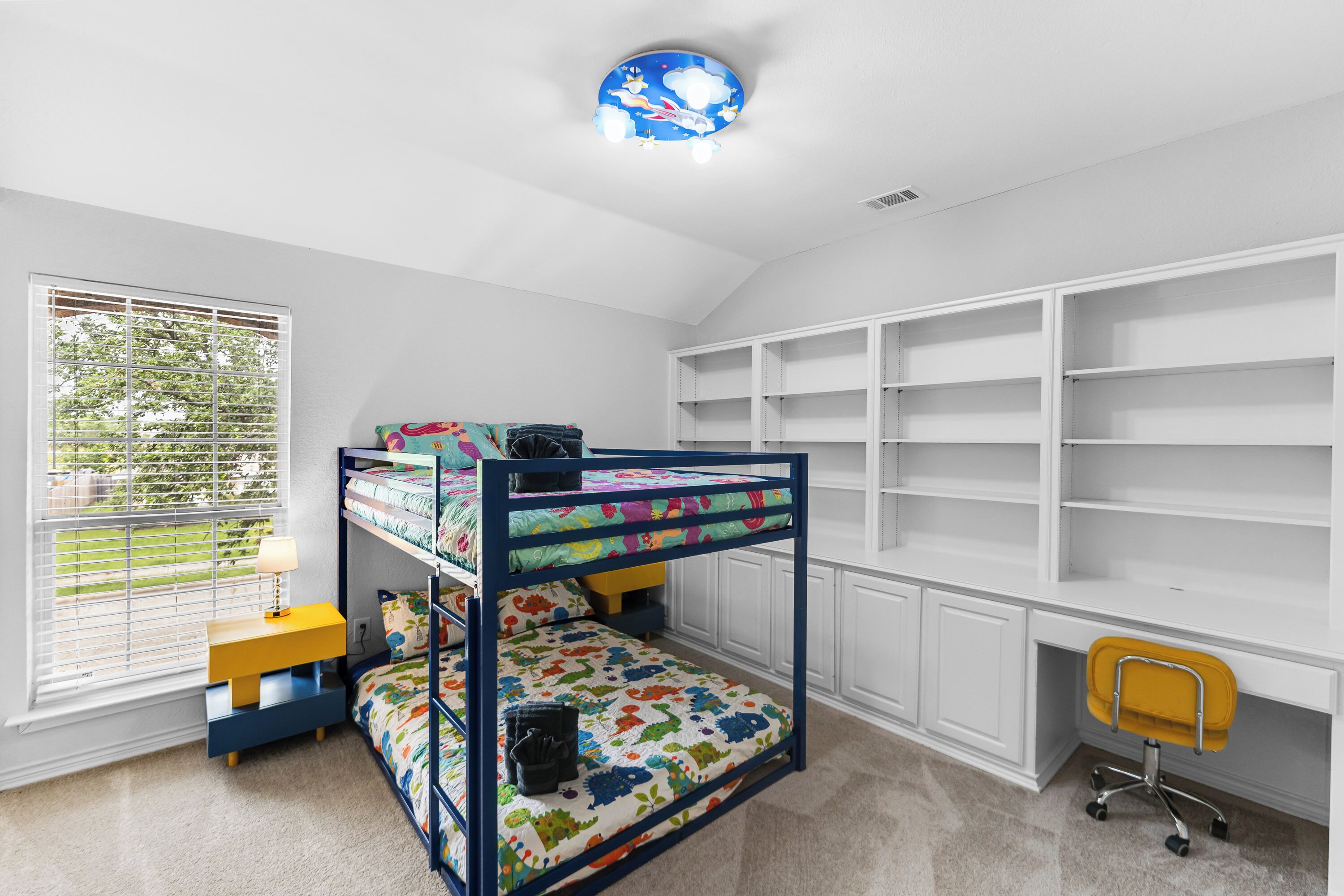 Habitación infantil con literas, un escritorio y estanterías.