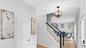 Un pasillo con puertas blancas, una escalera y un candelabro.