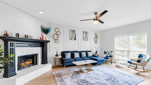 Una sala de estar moderna con chimenea, sofá azul y detalles decorativos en la pared.