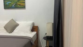 Un dormitorio con una cama, una mesita de noche con una lámpara y un cuadro en la pared.