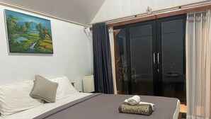 Una habitación de hotel con una cama, un cuadro de un paisaje, un armario y una cortina.