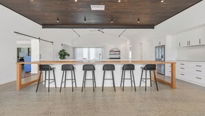Een moderne keuken met een centraal kookeiland, barkrukken en een groot raam.