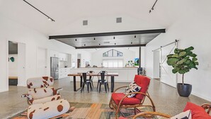 Een ruime woonkamer met een eettafel, een bank en een grote kamerplant.