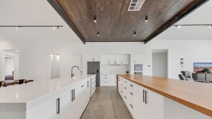 Een moderne keuken met witte kastjes, een houten aanrecht en een centraal eiland.