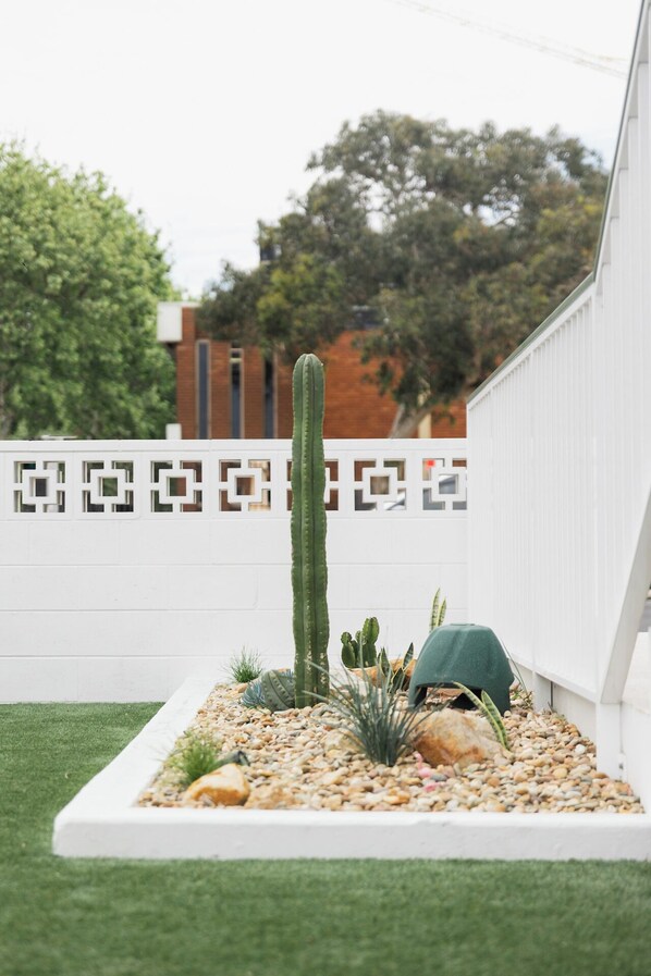 Un jardin de cactus comprenant un grand cactus, des cactus plus petits et des plantes ornementales, le tout disposé dans un pot blanc.