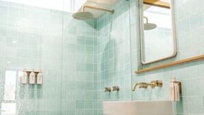 A bathroom with a sink, two showerheads, and a mirror.