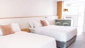 A hotel room with two beds, a small kitchenette, and a view of the city.