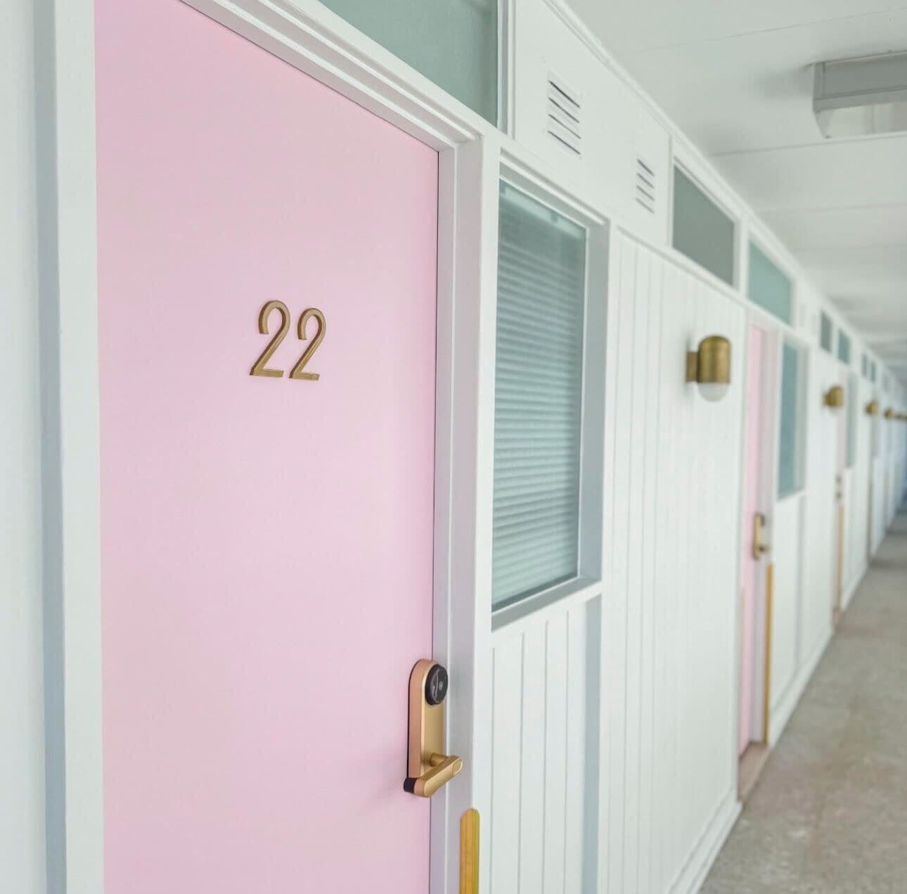 Una hilera de habitaciones de hotel con números 22, cada una con un esquema de colores único y un diseño moderno y minimalista.