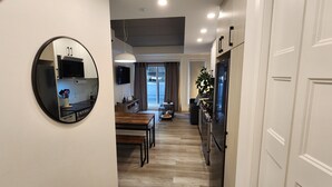 A modern kitchen with a round mirror, wooden flooring, and a dining area with a table and chairs. - In the heart of the city, modern, comfortable, fully-equipped urban accommodation. (Québec)