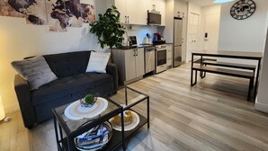 A modern living room with a sofa, coffee table, and a dining area with a bench. - In the heart of the city, modern, comfortable, fully-equipped urban accommodation. (Québec)