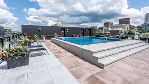 A rooftop pool with a view of the city skyline, surrounded by lounge chairs and potted plants. - In the heart of the city, modern, comfortable, fully-equipped urban accommodation. (Québec)