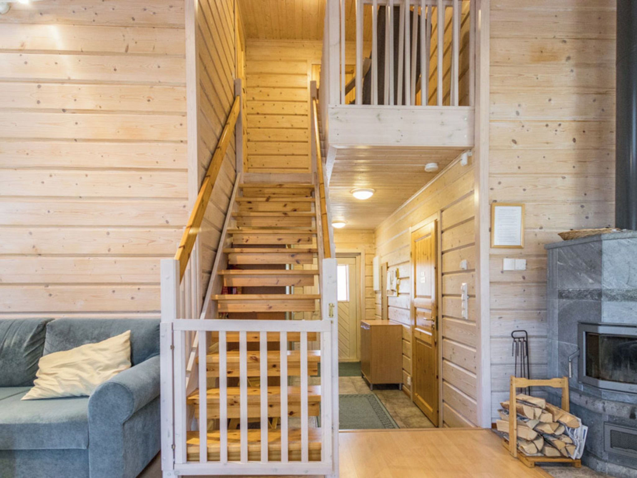 Un intérieur en bois comprenant un escalier, un canapé, une cheminée et un meuble en bois.