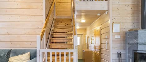 Un intérieur en bois comprenant un escalier, un canapé, une cheminée et un meuble en bois.