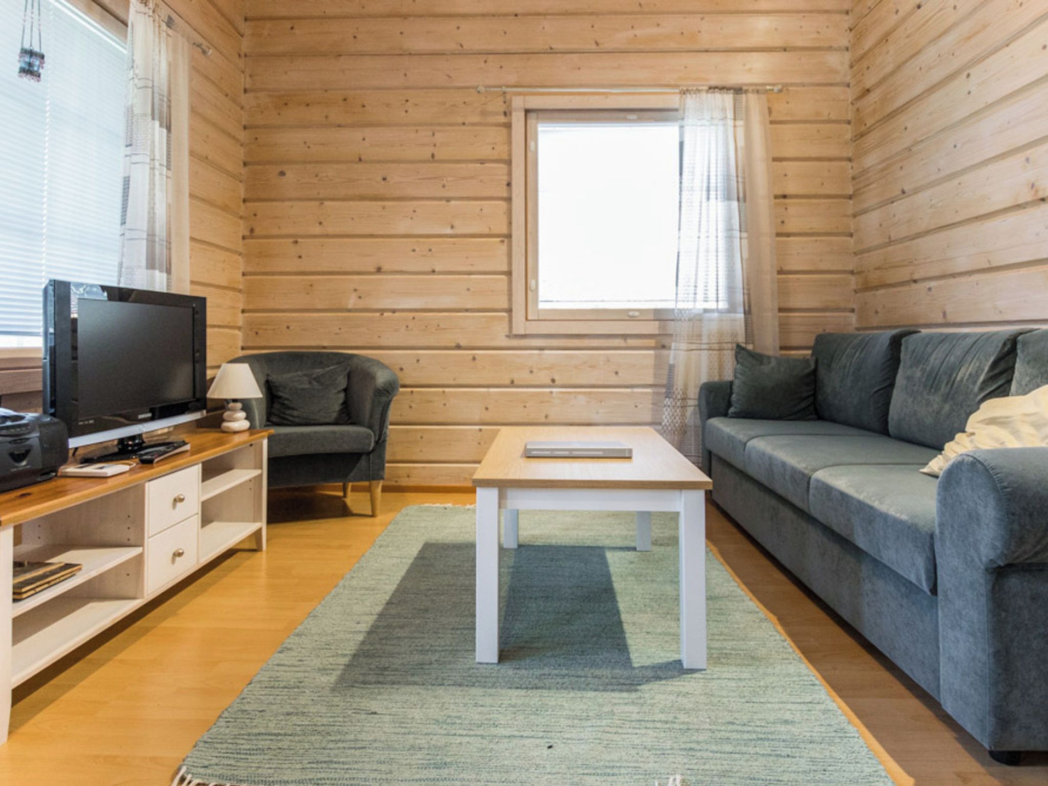 Een knus kamer in chaletstijl, met televisie, zithoek en raam.