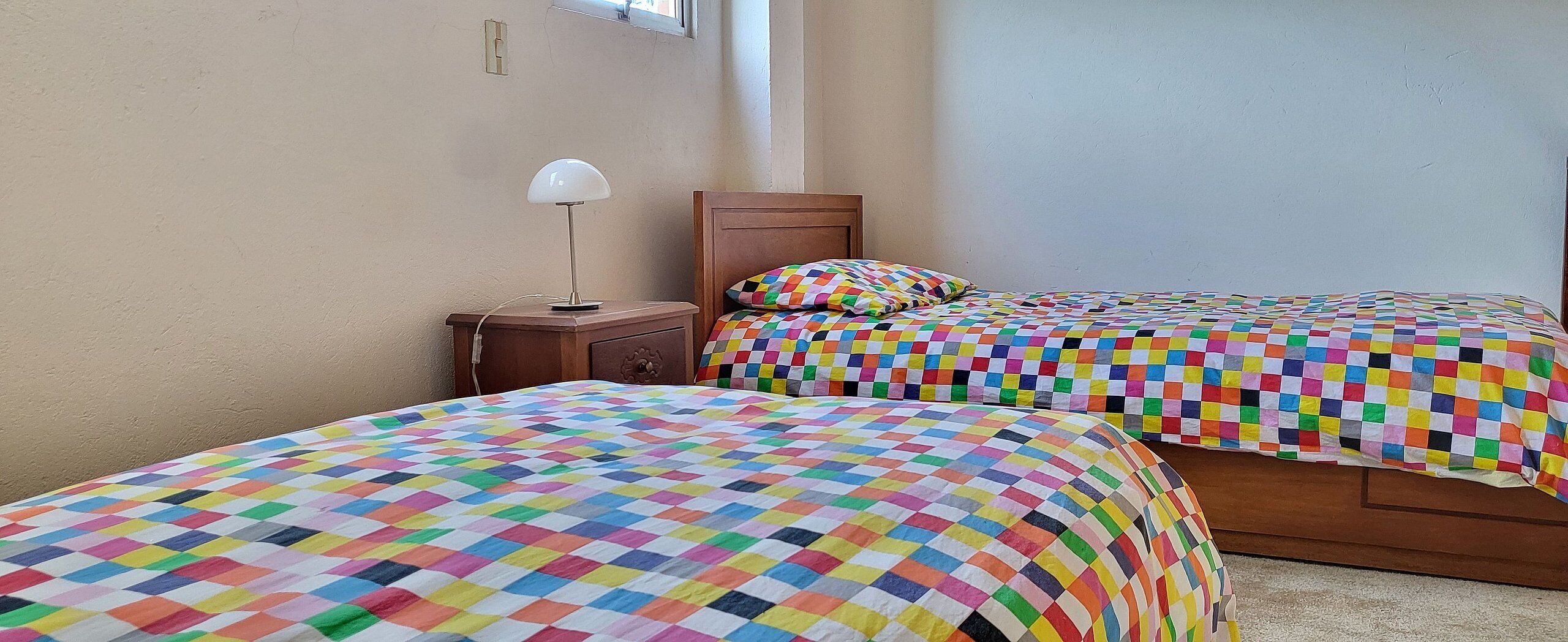 Un dormitorio con dos camas, cada una con una colcha de cuadros colorida.