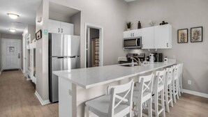 A modern kitchen with a central island, stainless steel appliances, and white cabinetry. - ~VIP by the Beach~ Chair Service Included (Destin)