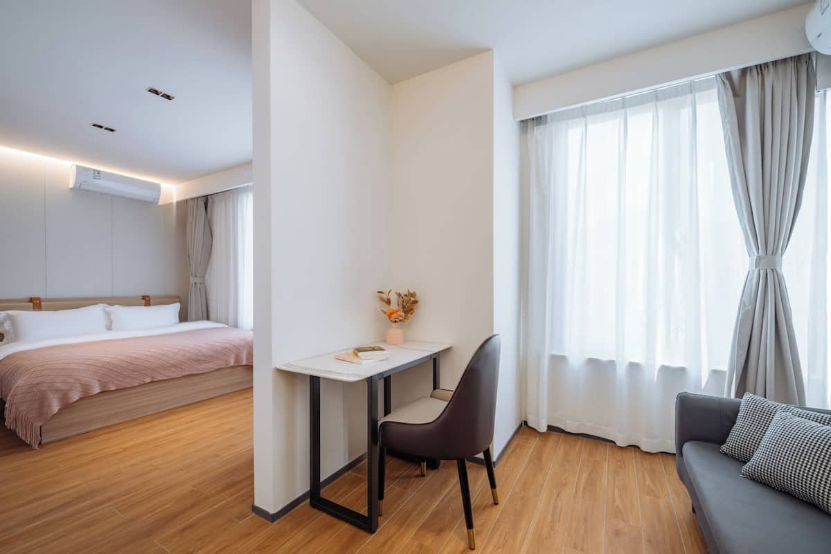 A modern hotel room with a bed, a desk, a chair, and a sofa.
