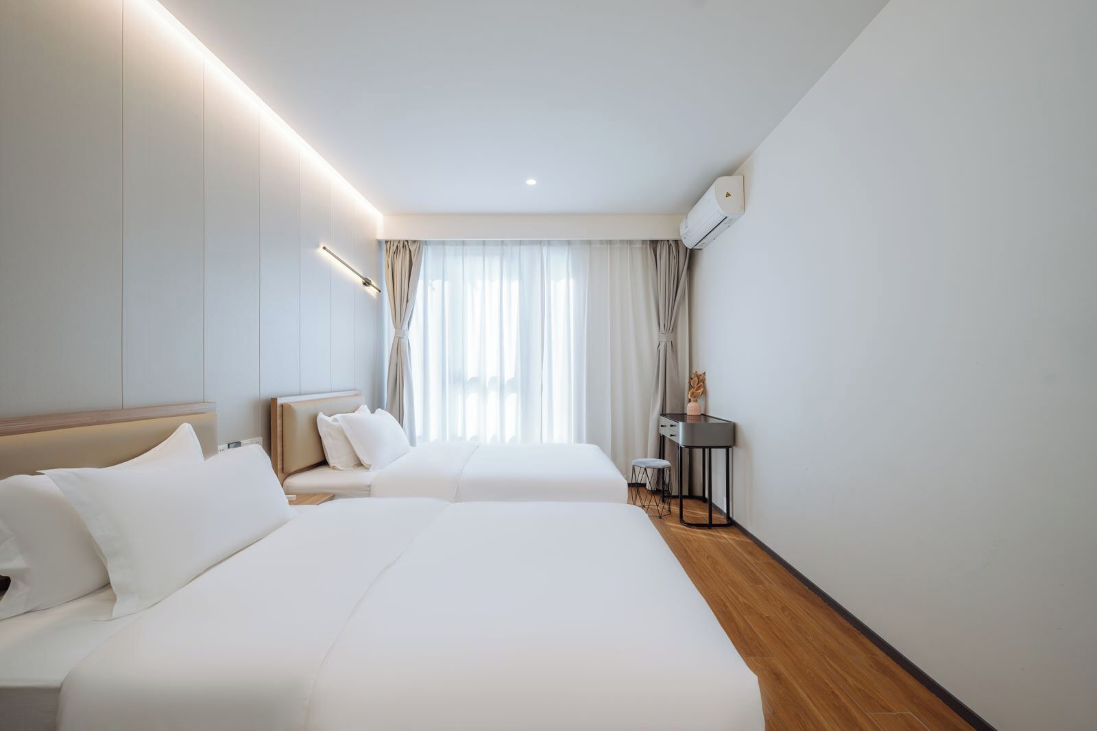 Ein Hotelzimmer mit zwei Betten, einem Schreibtisch und einem Stuhl.
