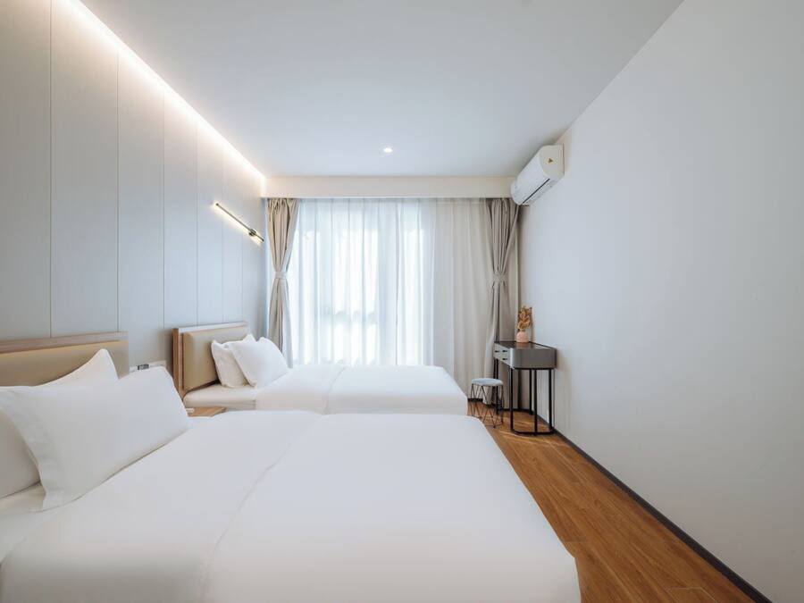 A hotel room with two beds, a desk, and a chair.